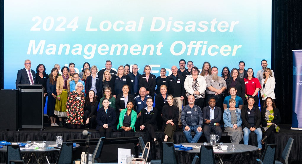 A group of people posing at a stage. "2024 Local Disaster Management Officer" at the back white text on blue